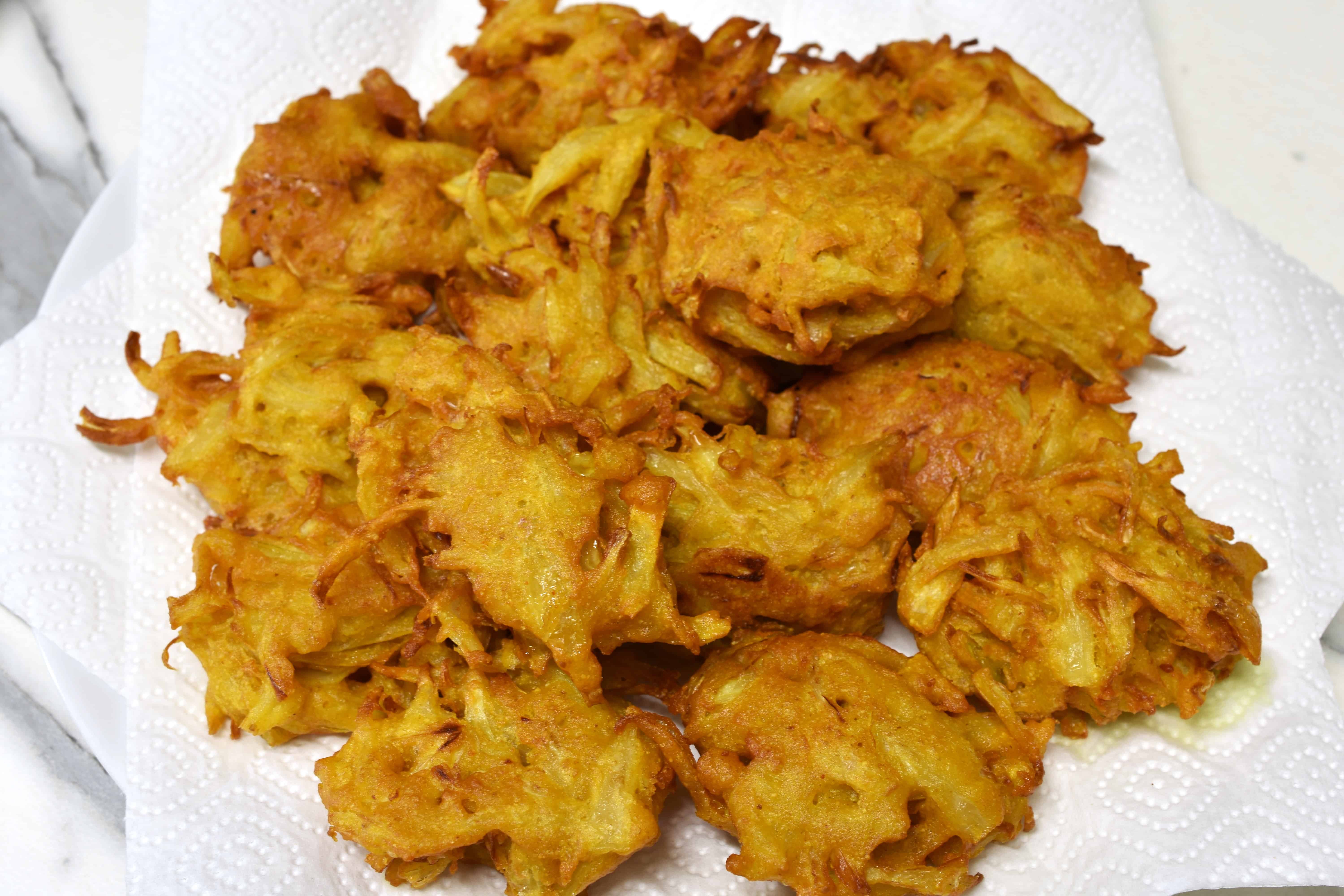 Fried onion bhaji on a plate with absorbent kitchen paper.