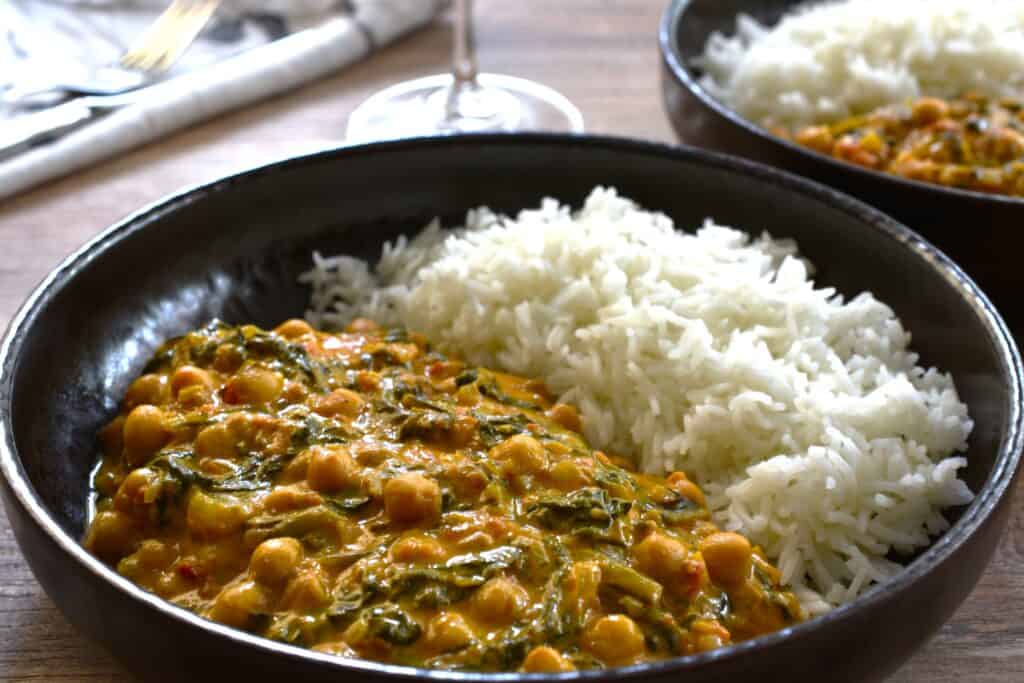 Plates of quick vegan chickpea and spinach curry with white basmati rice.