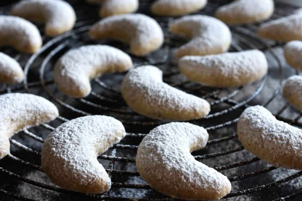 A close-up image of Vanillekipferl (vanilla crescent cookies) on a round cooling rack.