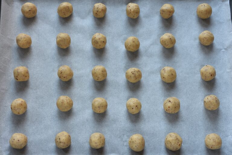 Balls of vegan Vanillekipferl dough on a baking sheet.