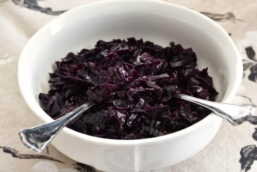 Balsamic red cabbage in a serving bowl with a fork and spoon.