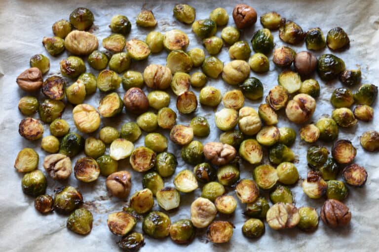 Roasted Brussels sprouts and chestnuts on an oven tray.