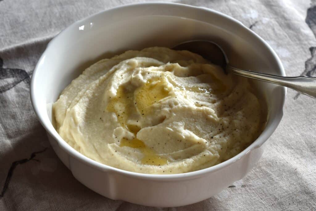 Vegan celeriac mash in a serving bowl with a spoon.