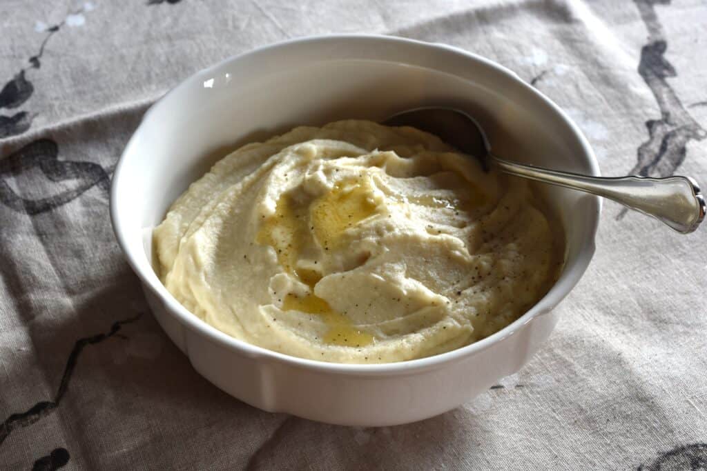 Vegan celeriac mash in a serving bowl with a spoon.