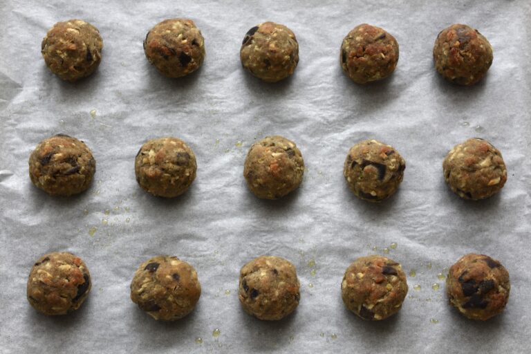 Baked polpette di melanzane vegan eggplant meatballs on a baking tray.