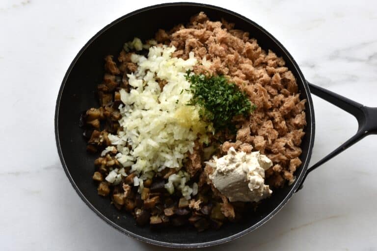 Diced aubergine, bread, onion, garlic, parsley and vegan cream cheese in a pan.