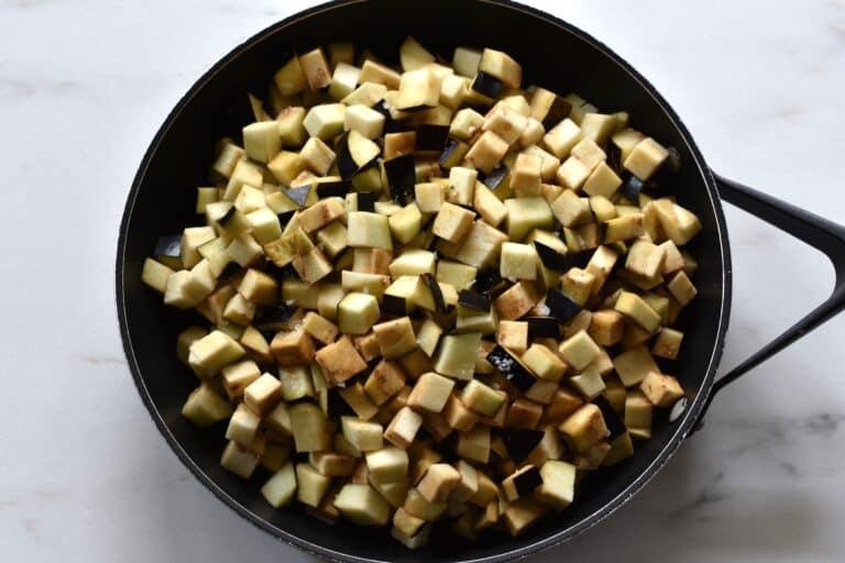 Diced raw aubergine in a pan.