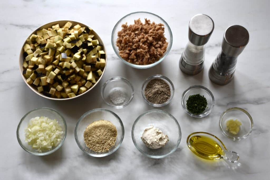 Ingredients for polpette di melanzane vegan egglant meatballs in glass bowls on a worktop.