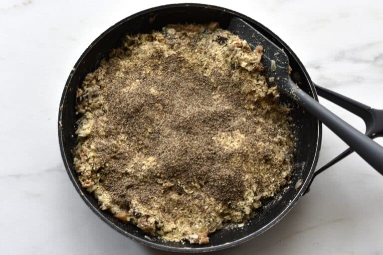 Polpette di melanzane vegan eggplant mixture in a pan with nutritional yeast flakes and ground chia seeds.