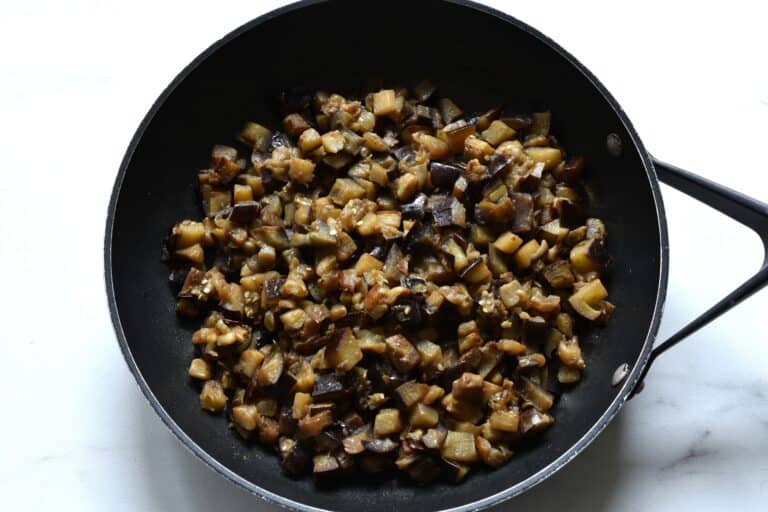 Sautéed diced aubergine/eggplant in pan on a worktop