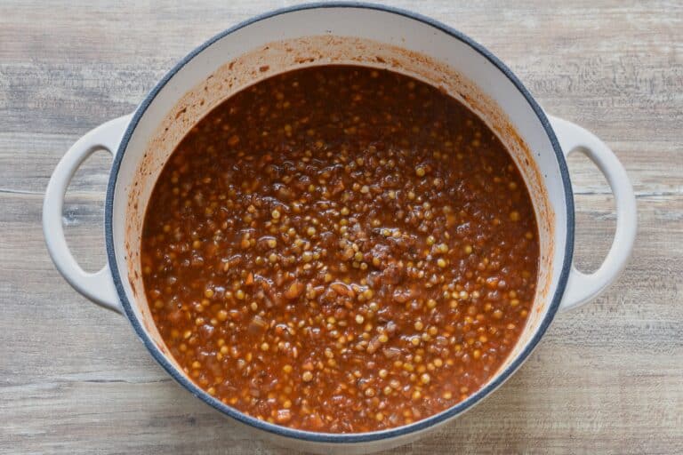 Semi-cooked vegan lentil ragu in a cast iron pan.