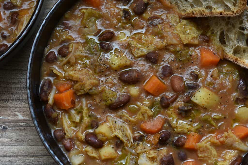 A close-up image of Italian stregoni bean soup with slices of bruschetta in a brown bowl.