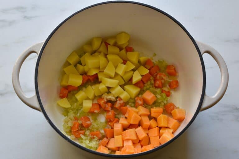 Chopped onion and celery, diced carrot, pumpkin and potatoes, and minced garlic in a pan with olive oil.