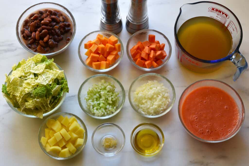 Ingredients for stregoni bean soup in individual glass bowls on a kitchen worktop.