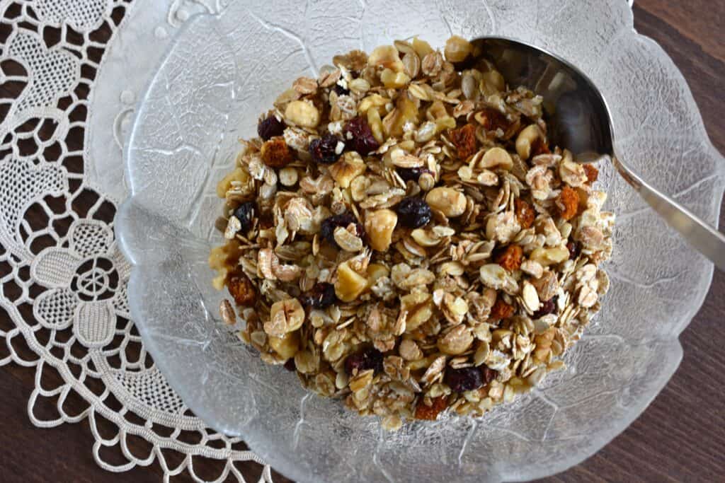 Raw vegan granola in a glass bowl with a spoon.