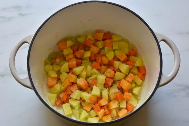 Sautéed onion, celery, carrot, pumpkin and garlic in a pan.