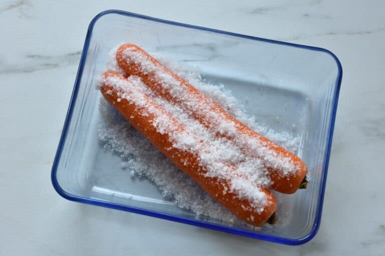 Two carrots covered in coarse salt.