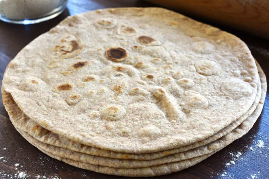 Four piadinas (Italian flatbread) made with farro flour, stacked up on a board.