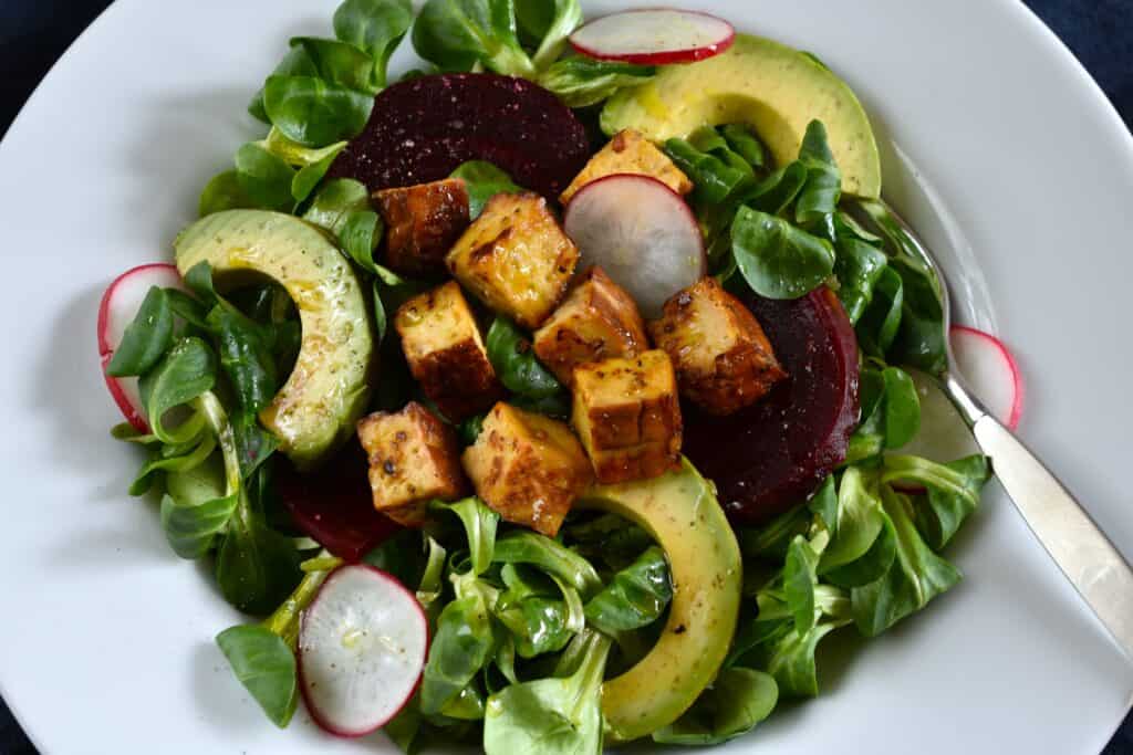 A close-up image of lamb's lettuce salad with smoked tofu, beetroot and avocado.