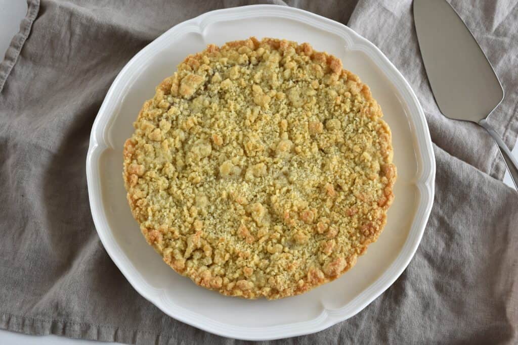 A whole vegan Italian crumble cake (sbriciolata or sbrisolona) with raspberry jam filling.