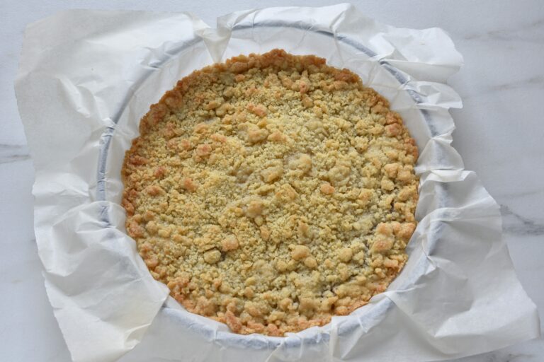 Baked vegan crumble cake with a raspberry filling in a dish with greaseproof paper.