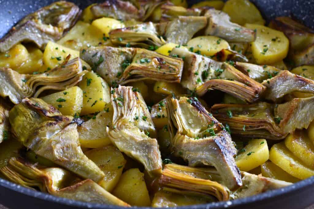 Italian-style artichokes and potatoes in a pan.