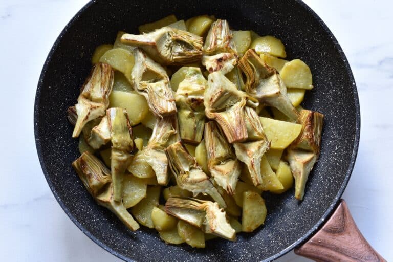 Sautéed artichokes and potatoes in a pan.