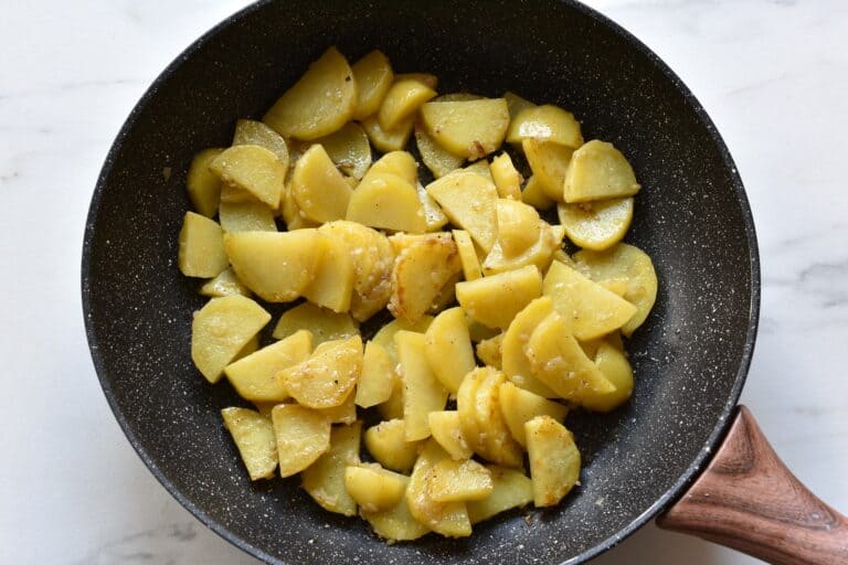 Sautéed potatoes with onion and garlic in a pan.