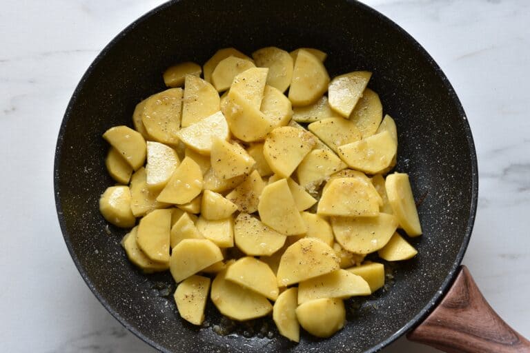 Slices of potatoes seasoned with salt, pepper and sautéed onion and garlic.