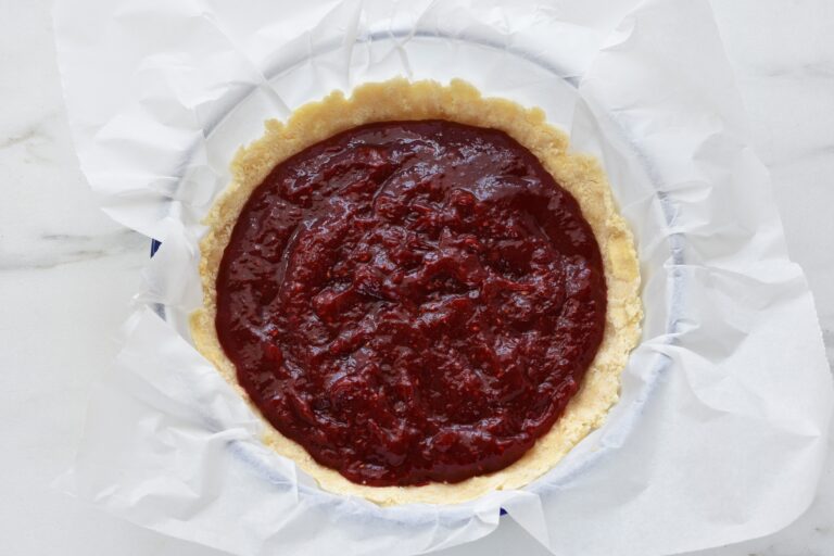 The base of a vegan crumble cake with raspberry filling in a bowl with greaseproof paper.