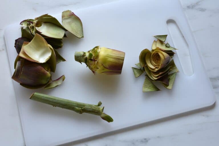 Trimming an artichoke on a chopping board.