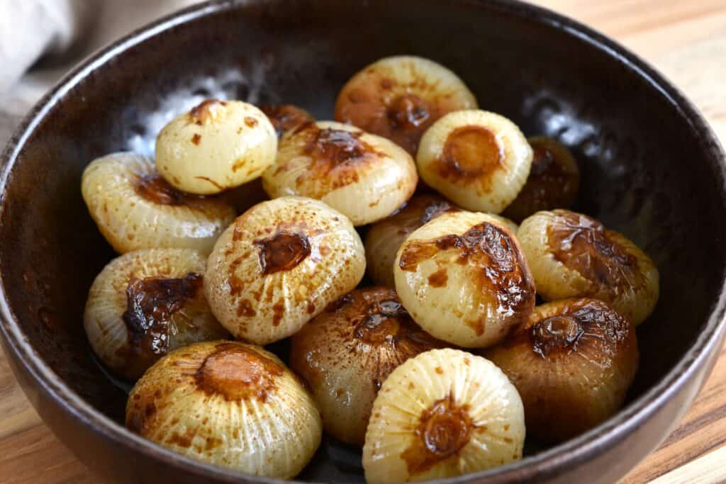 A close-up image of roasted balsamic borettane onions in a brown bowl.