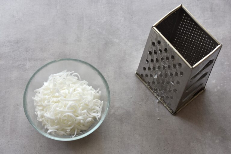 Grated soap in a glass bowl with a box grater.