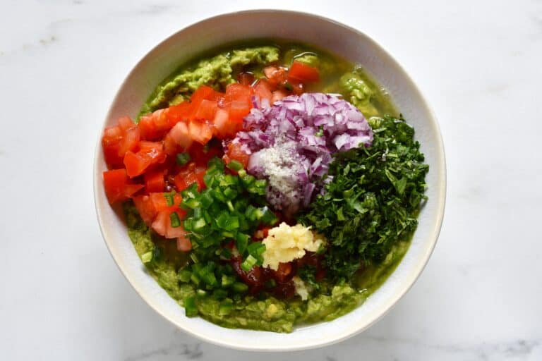 Mashed avocado, chopped tomato, red onion, minced garlic, lime juice, sea salt and chopped green coriander leaf in a bowl