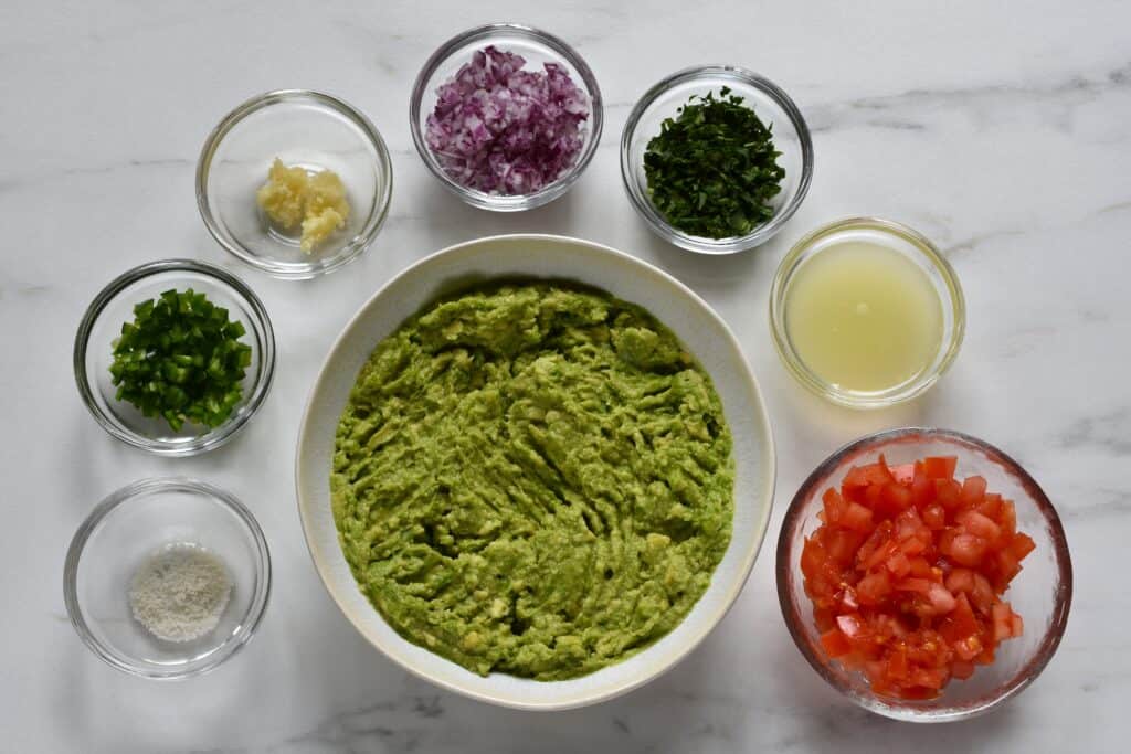 Recipe ingredients for vegan guacamole in individual glass bowls.