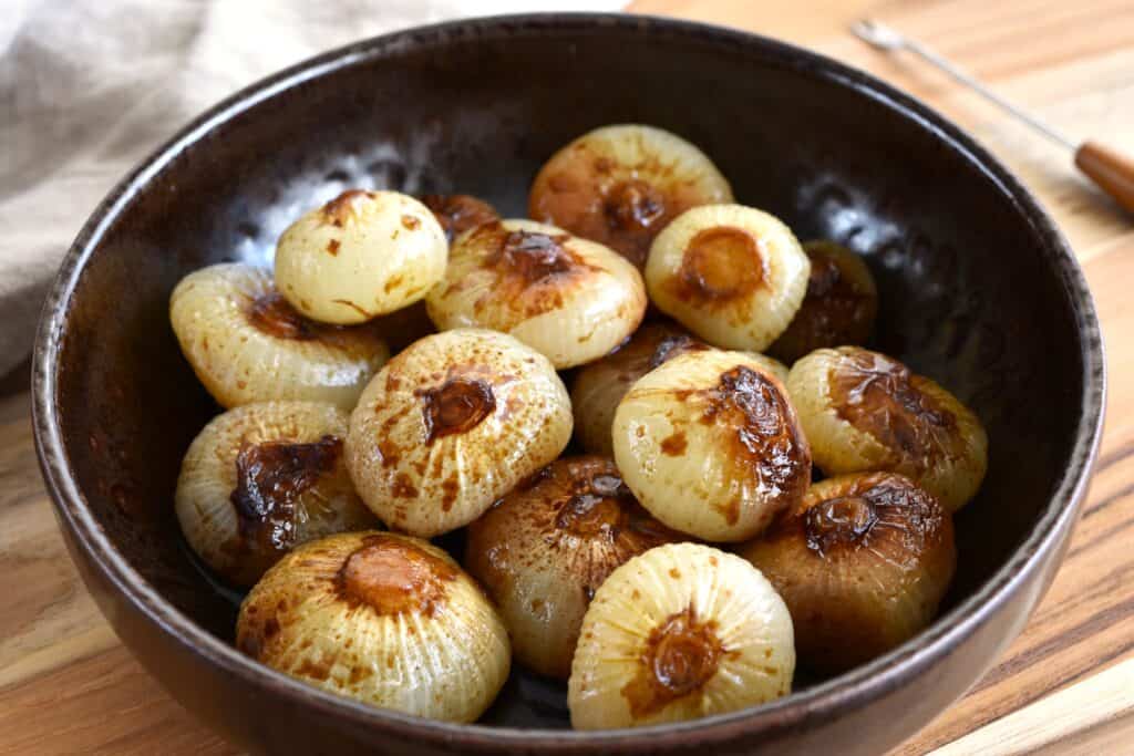 Roasted Italian borettane onions in balsamic vinegar in a brown bowl.