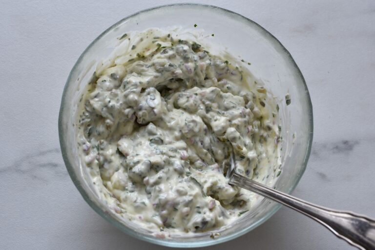 Homemade vegan tartare sauce in a glass bowl with a spoon.