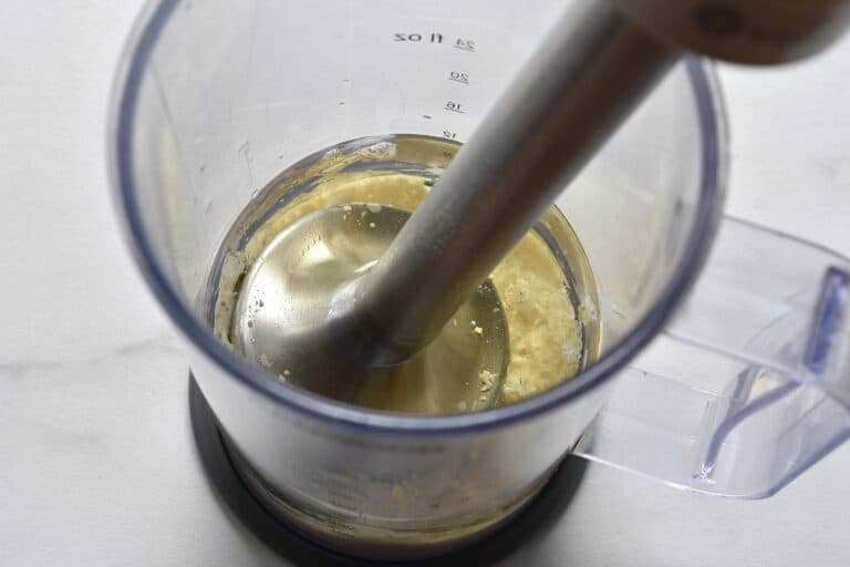 Sunflower oil, soy milk, lemon juice, mustard, and salt in a blender beaker wtih an immersion blender.