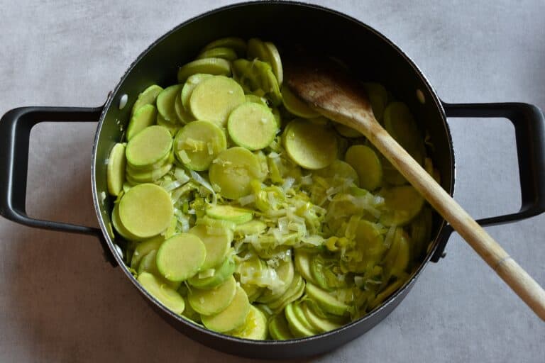 Partially cooked trombetta and leek in a pan.