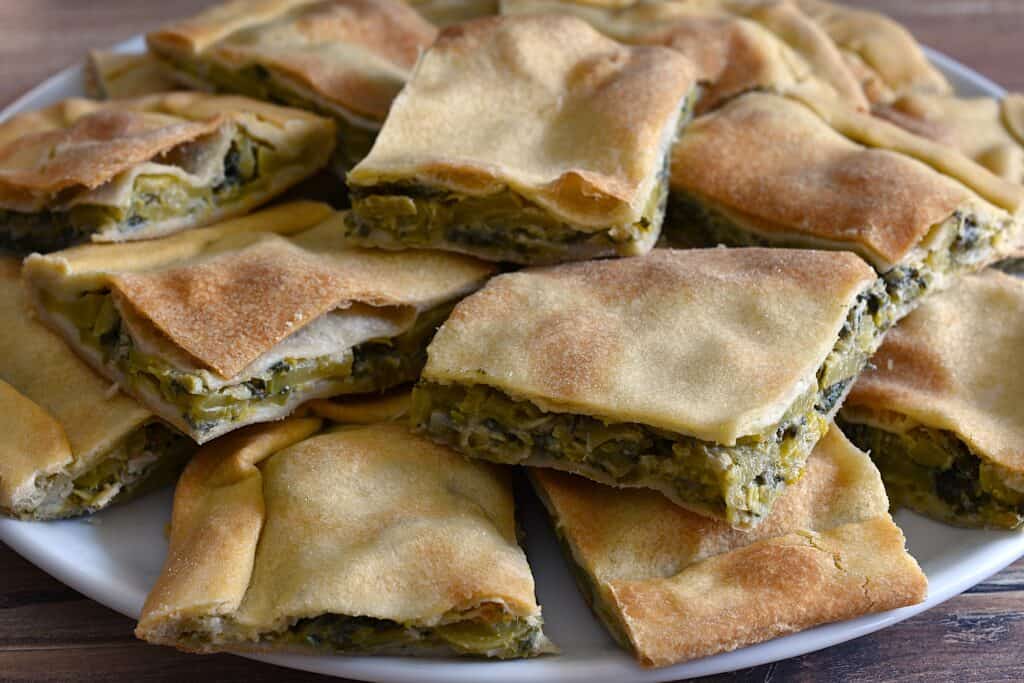 Pieces of torta verde di Sanremo (Italian savoury green vegetable pie) on a serving platter.