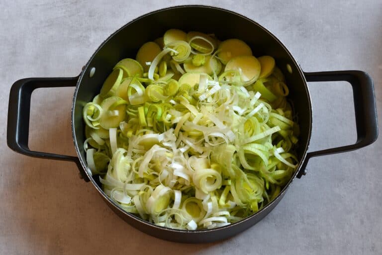 Sliced trombetta and leek in a pan with olive oil.