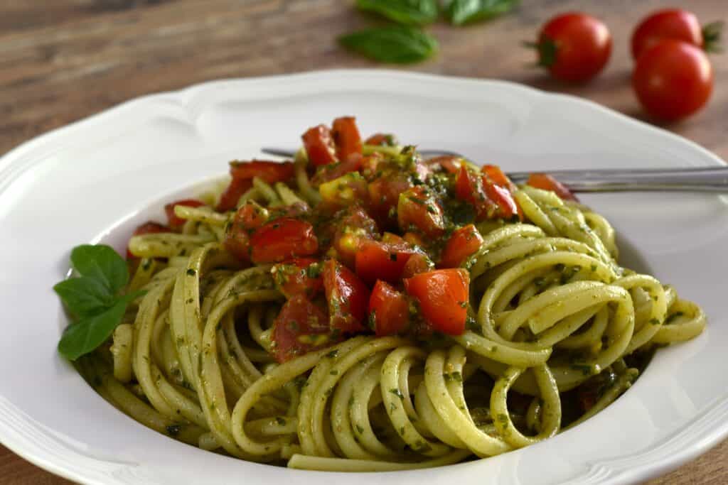 A close-up image of pesto and cherry tomato linguine pasta.