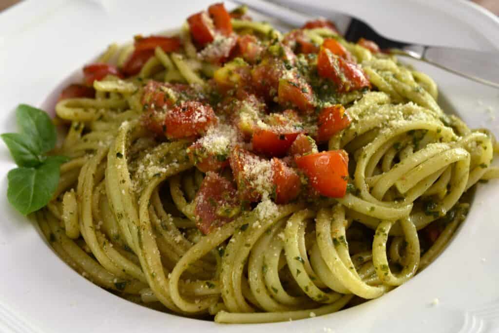 A close-up image of pesto and cherry tomato pasta.