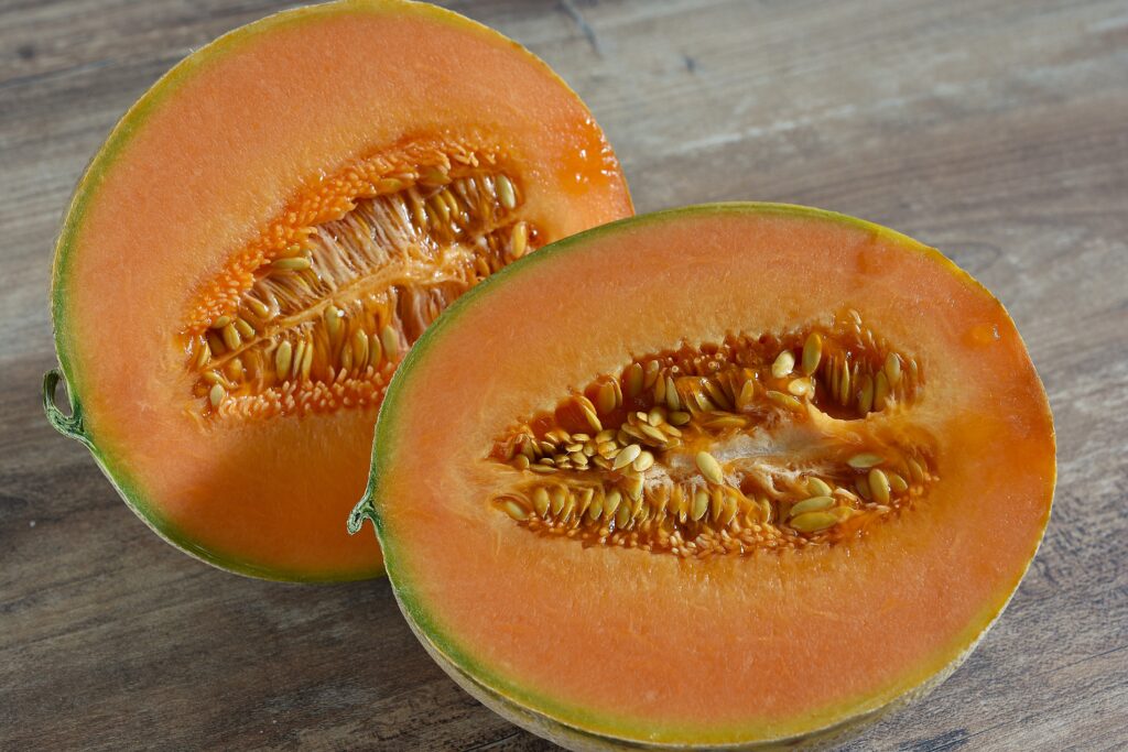 An Italian netted (Cantaloupe) melon halved on a wooden table.