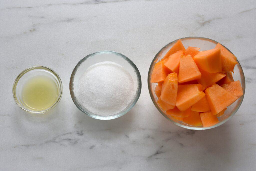 Chunks of melon, sugar, and lemon juice in individual glass bowls.