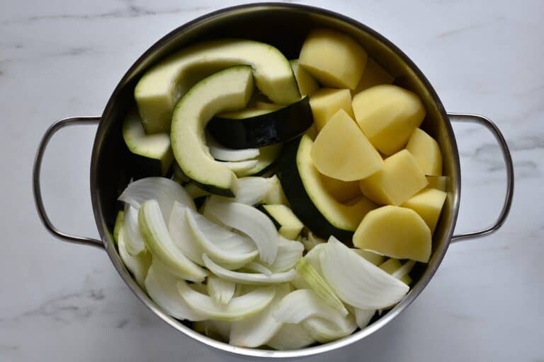 Chopped marrow, potatoes, and onion in a saucepan.