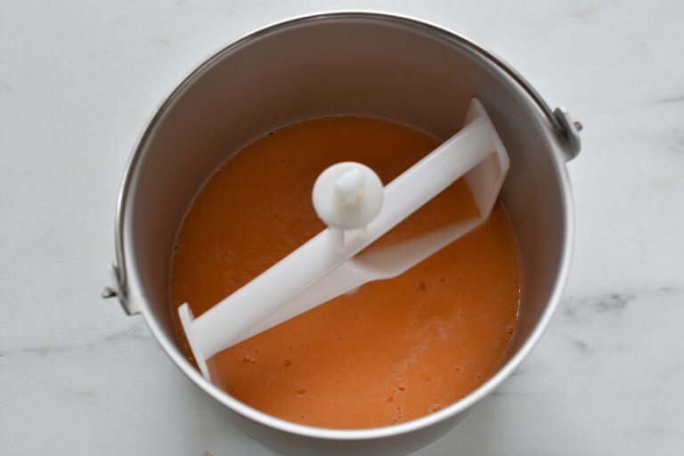 Melon sorbet mixture in the basket of an ice cream maker.