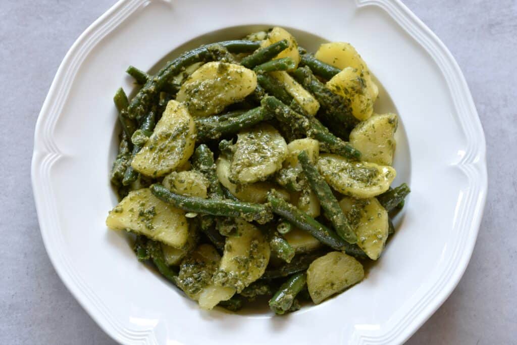 Potatoes, green beans and vegan basil pesto on a white plate.