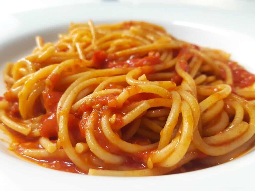 Italian spaghetti with fresh tomato sauce on a white pasta plate.