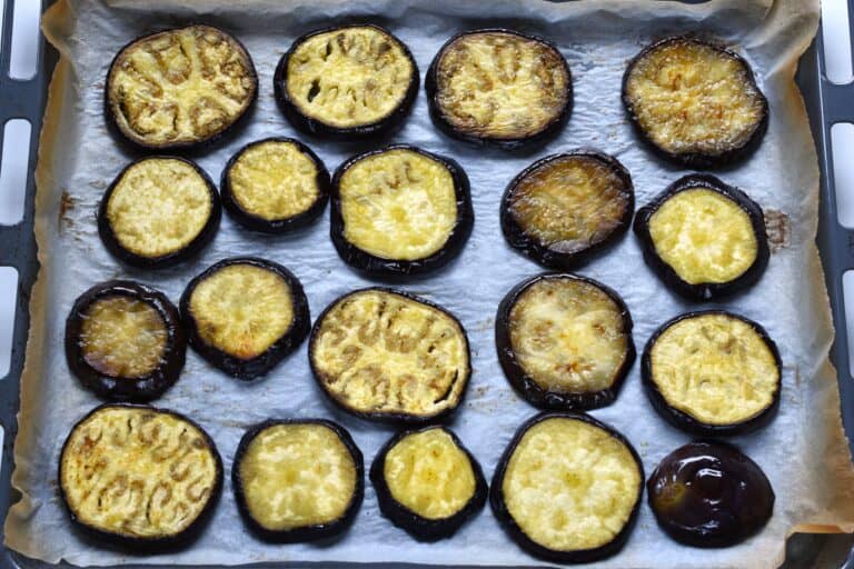 Aubergine (eggplant) slices on an oven tray after turning.